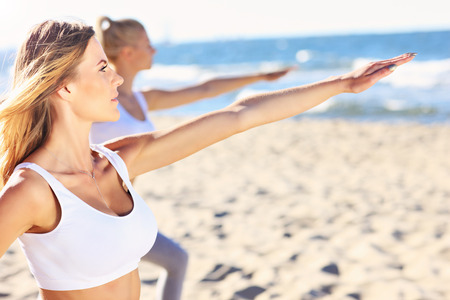 A picture of a group of women practising yoga on the beachの写真素材