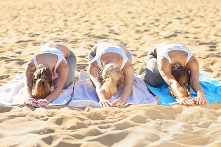A picture of a group of women practising yoga on the beachの写真素材