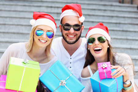 A picture of group of friends in Santa's hats sitting in the city with presentsの写真素材