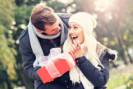 A picture of a young couple with a present in the parkの写真素材