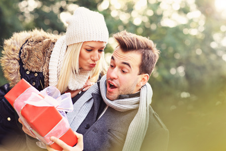 A picture of a young couple with a present in the parkの写真素材