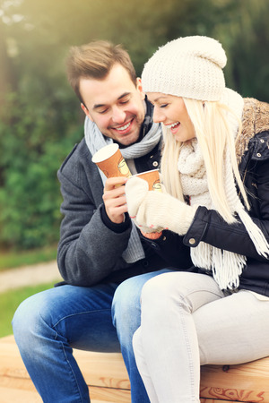 A picture of a young couple drinking coffee outdoorsの写真素材