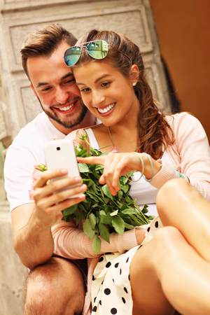 A picture of a young romantic couple using smartphone in the cityの写真素材