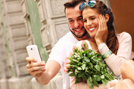 A picture of a young romantic couple using smartphone in the cityの写真素材