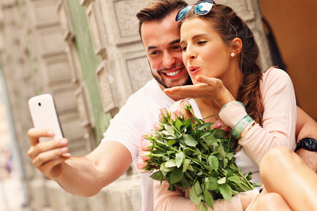 A picture of a young romantic couple using smartphone in the cityの写真素材