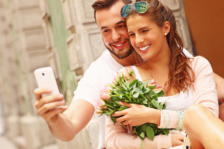 A picture of a young romantic couple using smartphone in the cityの写真素材
