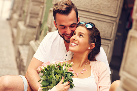 A picture of a young romantic couple with flowers in the cityの写真素材