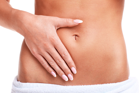 A midsection of fit woman's belly over white backgroundの写真素材