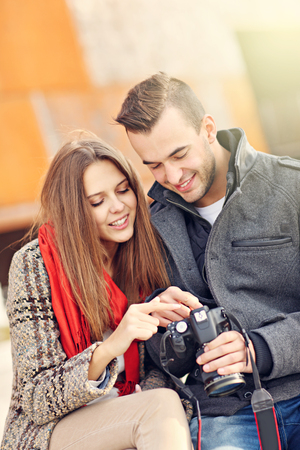 Picture of romantic couple sitting outside with cameraの写真素材
