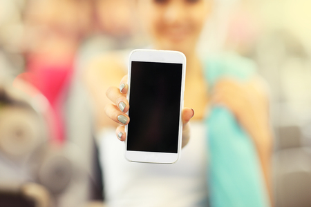 Picture of woman holding smartphone in gymの写真素材