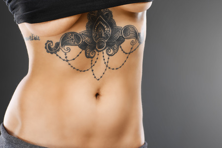 Midsection of female belly with tattooの写真素材