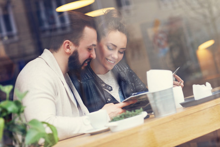 Happy couple choosing from menu in restaurantの写真素材