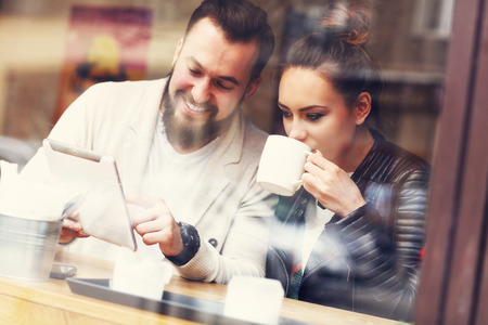 Picture of happy couple using tablet in restaurantの写真素材