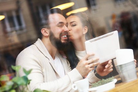 Picture of happy couple using tablet in restaurantの写真素材