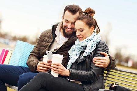 Picture of young couple sitting with shopping bags and smartphoneの写真素材