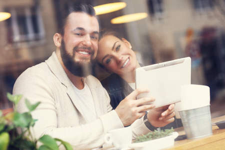 Picture of happy couple using tablet in restaurantの写真素材