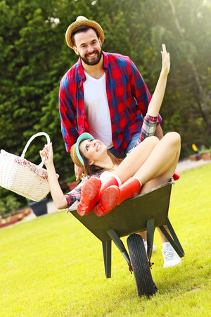 Picture of young couple having fun in the garden riding a barrowの写真素材