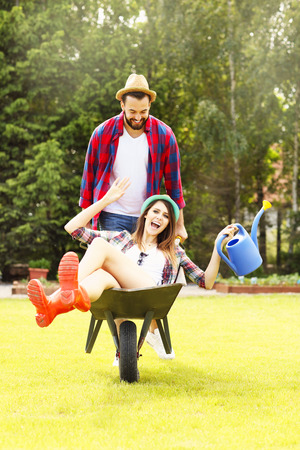 Picture of young couple having fun in the garden riding a barrowの写真素材