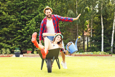 Picture of young couple having fun in the garden riding a barrowの写真素材