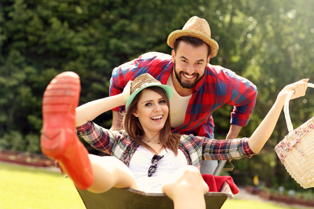 Picture of young couple having fun in the garden riding a barrowの写真素材