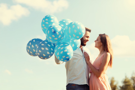 A picture of romantic couple standing outside with baloonsの写真素材