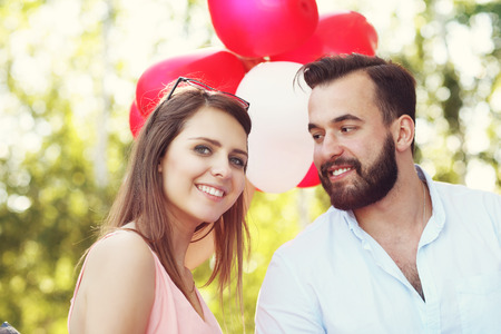 A picture of romantic couple standing outside with baloonsの写真素材