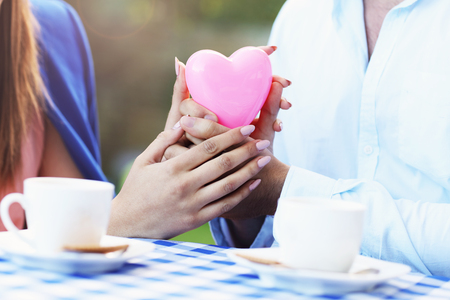 Picture of romantic couple holding hands in cafeの写真素材