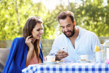 Picture of young couple using cellphone in a restaurantの写真素材