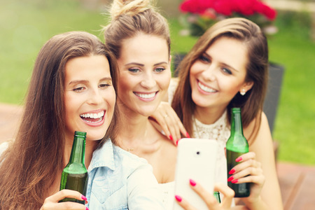 Picture presenting happy group of friends having a beer outdoorsの写真素材