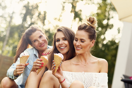 Picture presenting happy group of friends eating ice-cream outdoorsの写真素材