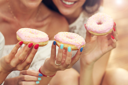 Picture presenting happy group of friends eating donuts outdoorsの写真素材