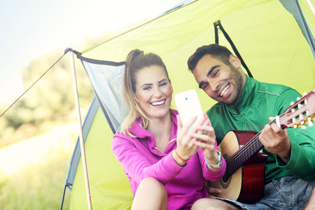 Picture of happy woman playing guitar outdoors and taking selfieの写真素材
