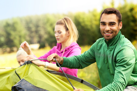 Group of friends putting up tent in the forestの写真素材