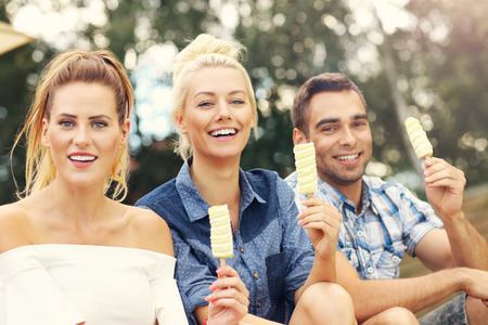 Picture presenting happy group of friends eating ice-cream outdoorsの写真素材