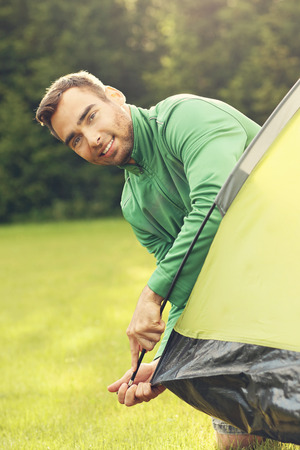 Picture of young man putting up tent in the forestの写真素材