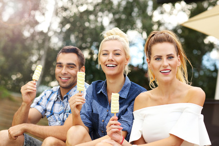 Picture presenting happy group of friends eating ice-cream outdoorsの写真素材