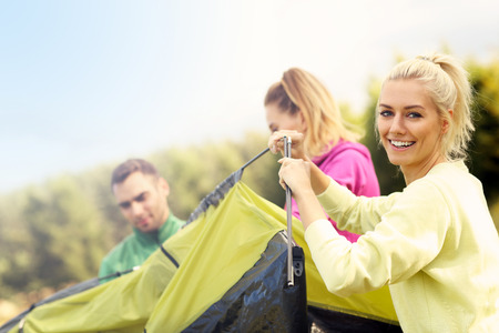 Group of friends putting up tent in the forestの写真素材