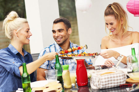 Picture presenting group of friends having barbecue partyの写真素材