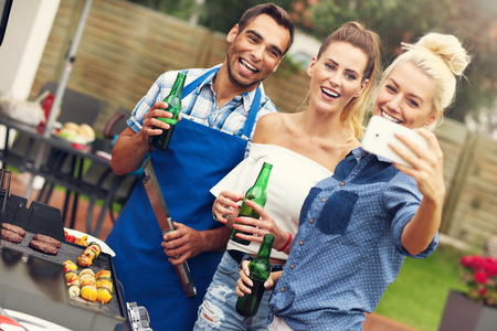 Picture presenting group of friends having barbecue party and taking selfieの写真素材