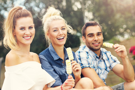 Picture presenting happy group of friends eating ice-cream outdoorsの写真素材