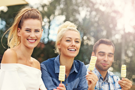 Picture presenting happy group of friends eating ice-cream outdoorsの写真素材