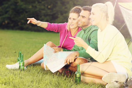 Picture showing group of friends camping in forest and looking at mapの写真素材