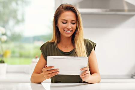 Picture of young woman with tablet in kitchenの写真素材