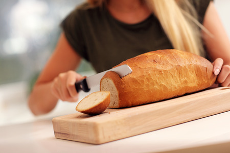 Picture of woman slicing loaf of breadの写真素材