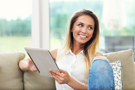Picture of young woman on couch with tabletの写真素材