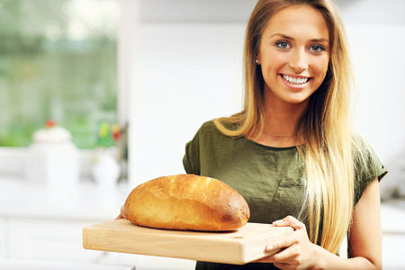 Picture of woman with loaf of bread in the kitchenの写真素材