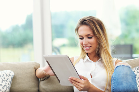 Picture of young woman on couch with tabletの写真素材