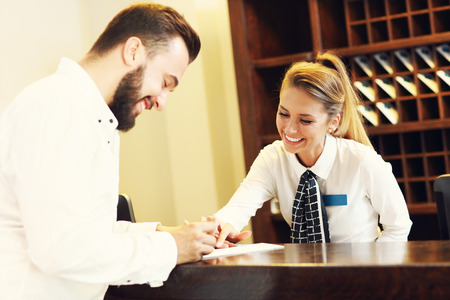 Picture of young businessman signing bill in hotelの写真素材