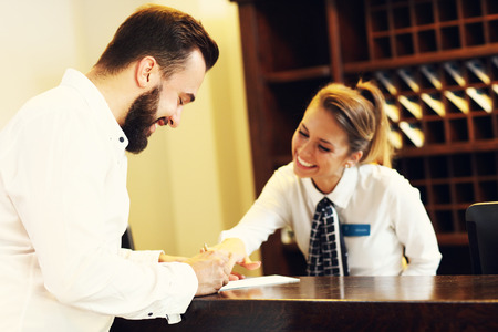 Picture of young businessman signing bill in hotelの写真素材
