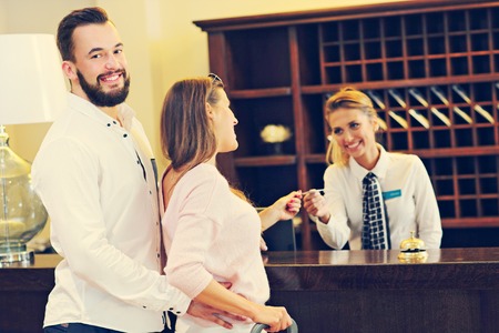 Picture of couple and receptionist at counter in hotelの写真素材